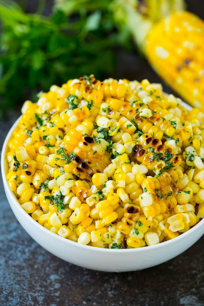 Grilled corn cut off the cob with herb butter in a bowl.