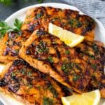 A plate of grilled salmon fillets garnished with lemon and herbs.