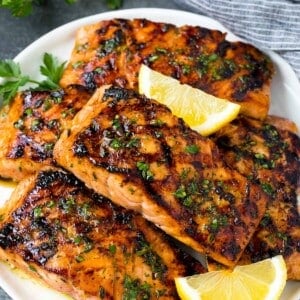 A plate of grilled salmon fillets garnished with lemon and herbs.