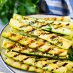 A plate of grilled zucchini garnished with lemon and herbs.