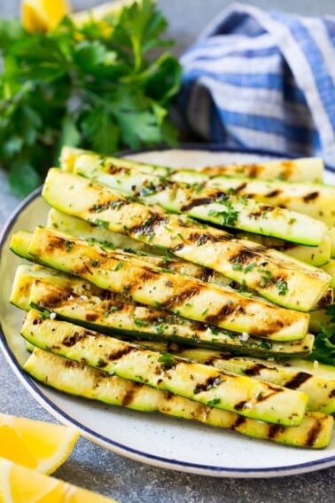 A plate of grilled zucchini garnished with lemon and herbs.