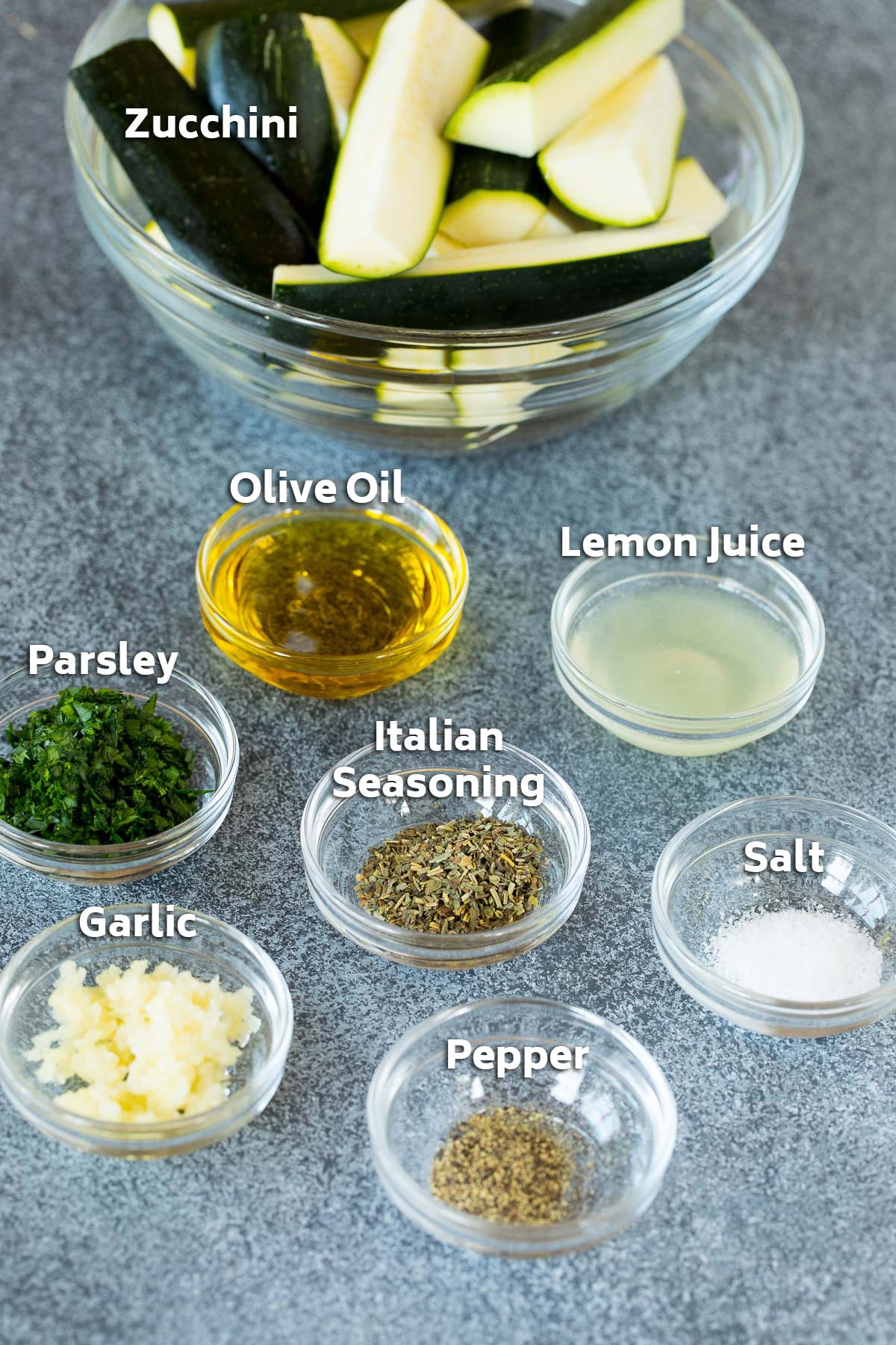 Bowls of ingredients including zucchini, olive oil, lemon juice, herbs and spices.