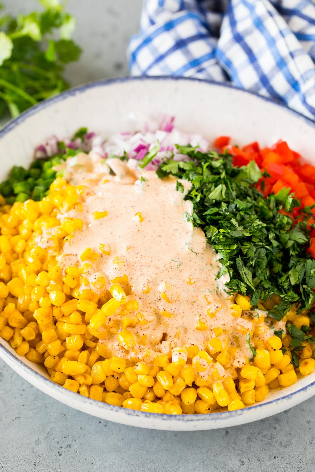 Dressing poured over a bowl of corn and vegetables.