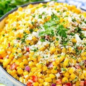 A bowl of Mexican corn salad topped with cheese and cilantro.