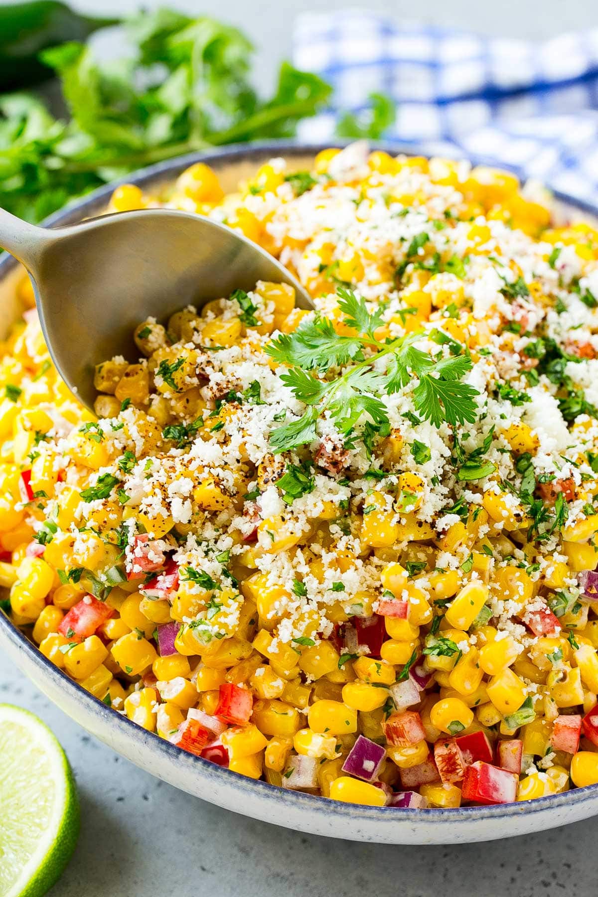 A serving spoon in a bowl of Mexican corn salad.