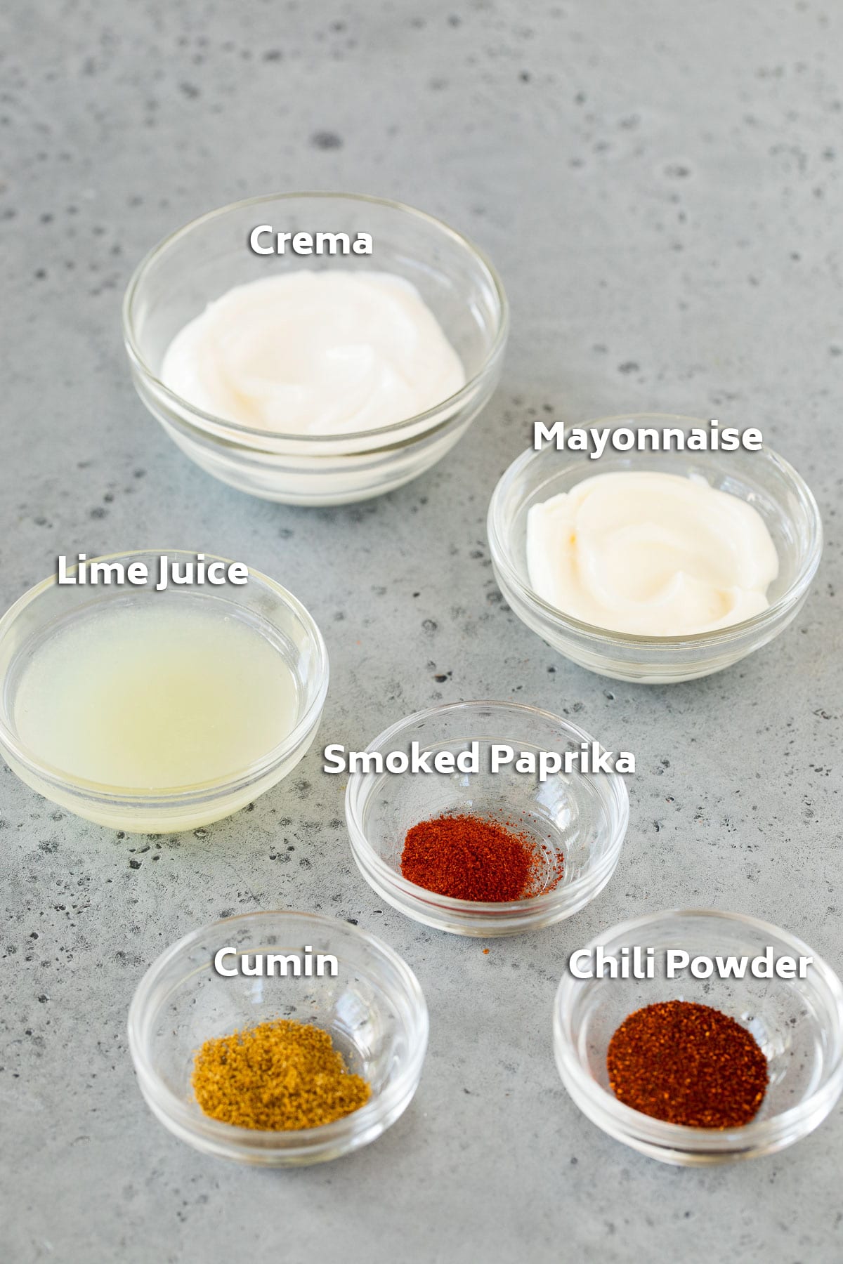 Bowls of dressing ingredients including mayonnaise, cream and spices.