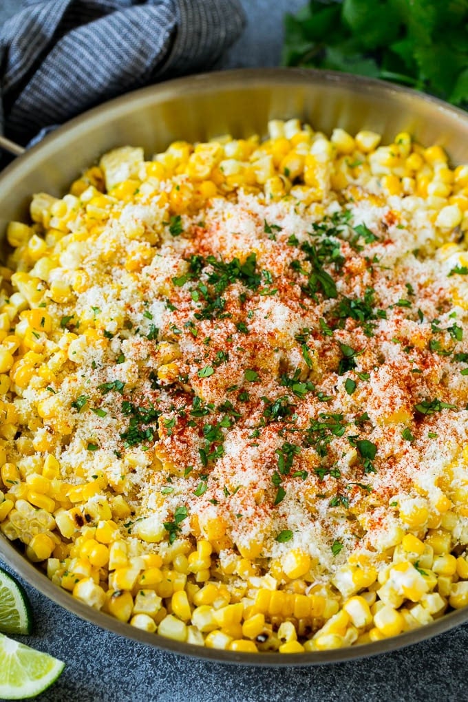 Mexican street corn in a pan topped with cotija cheese, chili power and cilantro.