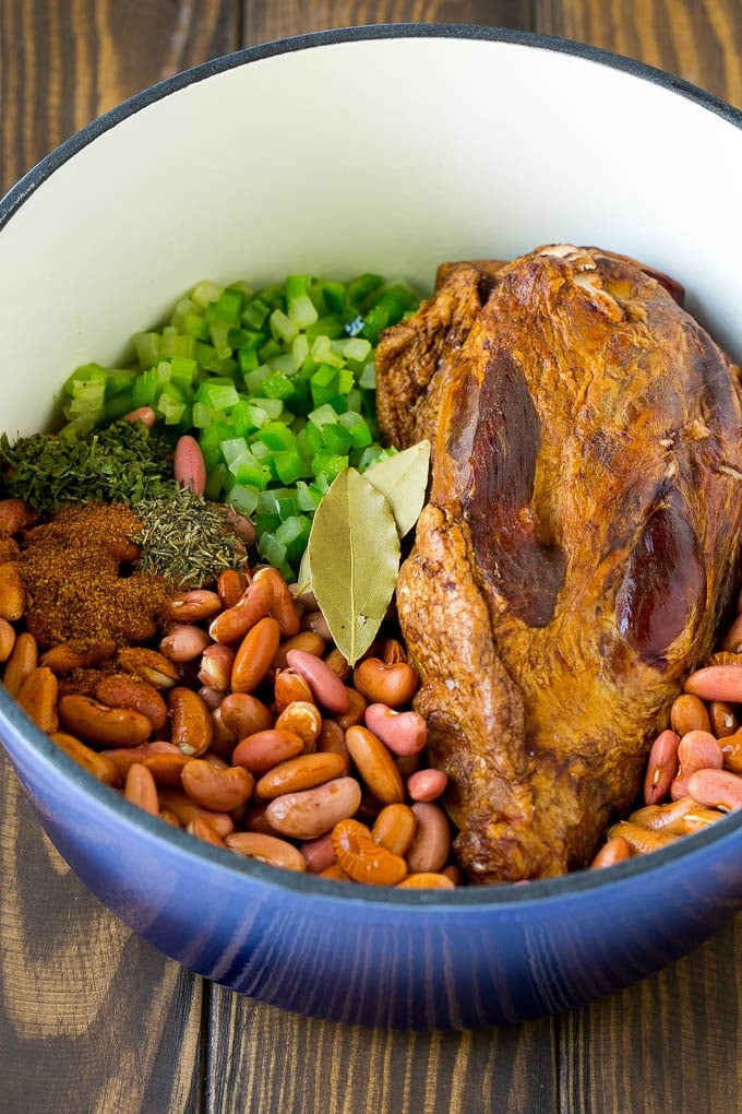 A pot of red beans with vegetables, seasonings and a ham hock.
