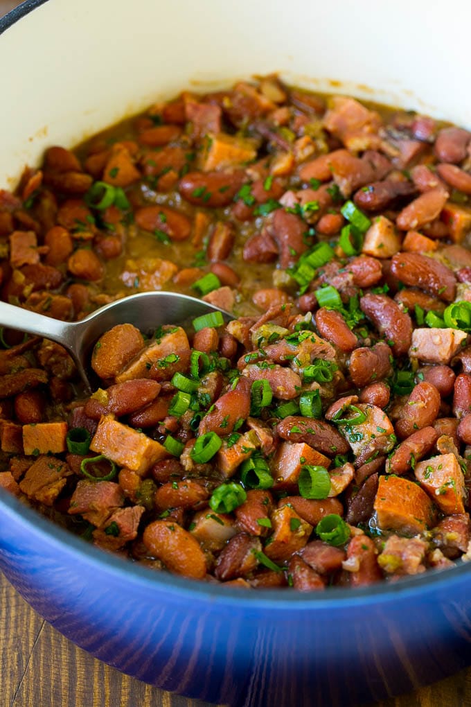 A pot of red beans and rice with sausage, topped with fresh herbs.