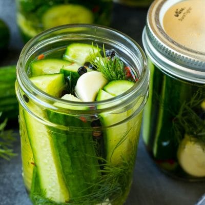 A jar of refrigerator pickles with cucumber spears, garlic and dill.