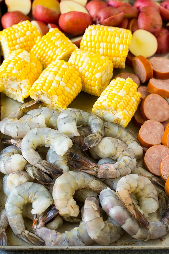 Raw shrimp, corn, sausage and potatoes on a sheet pan.