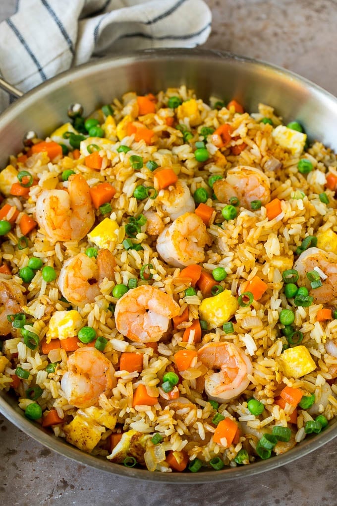 A pan of shrimp fried rice with eggs and vegetables.