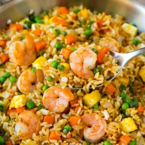 A serving spoon in a pan of shrimp fried rice.