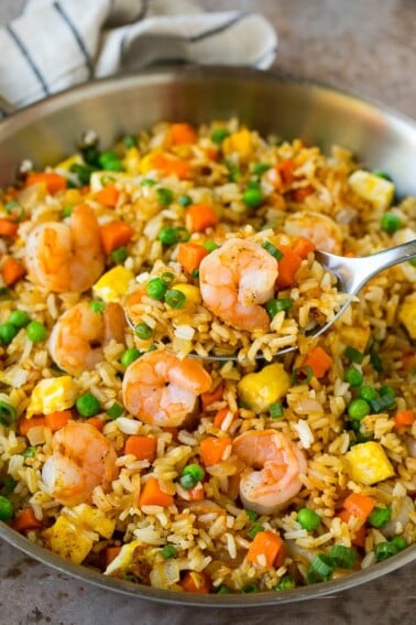 A serving spoon in a pan of shrimp fried rice.