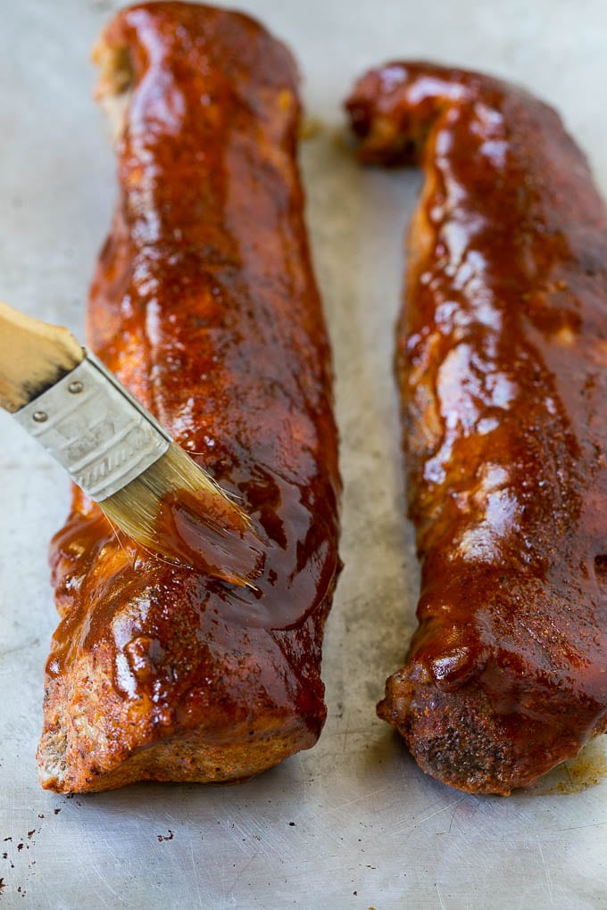 BBQ sauce being brushed over smoked pork loin.