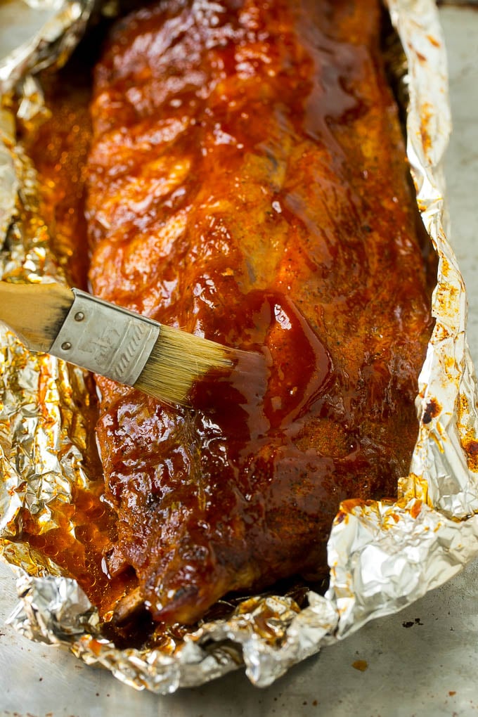 A brush basting smoked ribs with BBQ sauce.
