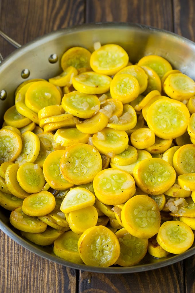 Yellow squash and onions in a frying pan.