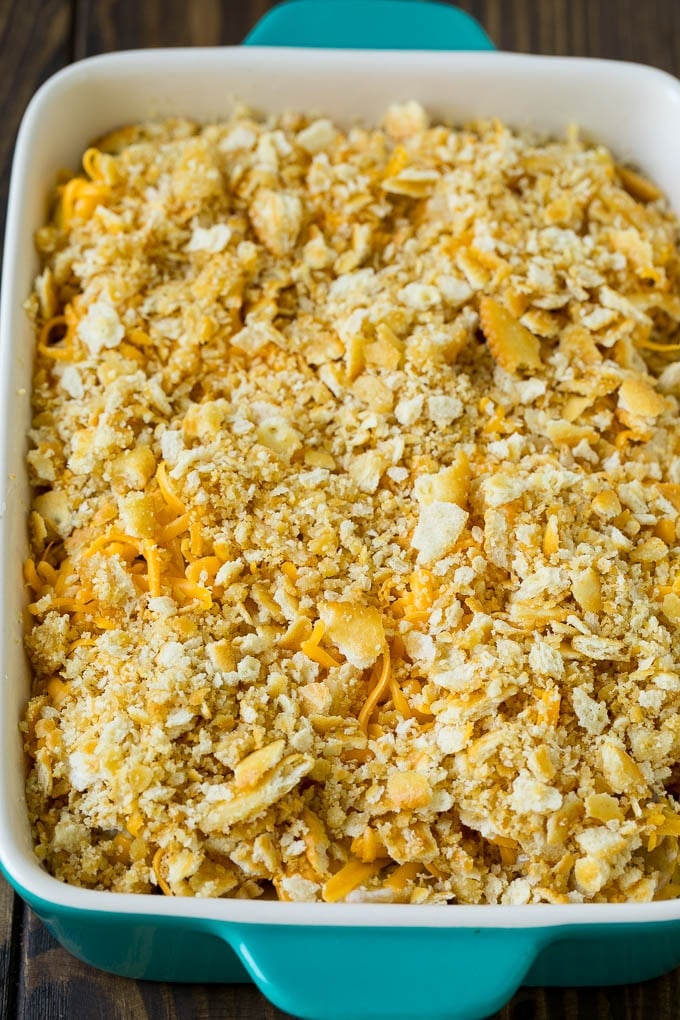 Squash in a baking dish topped with cracker crumbs and cheddar cheese.