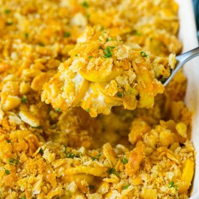 A spoon serving up a portion of cheesy squash casserole.