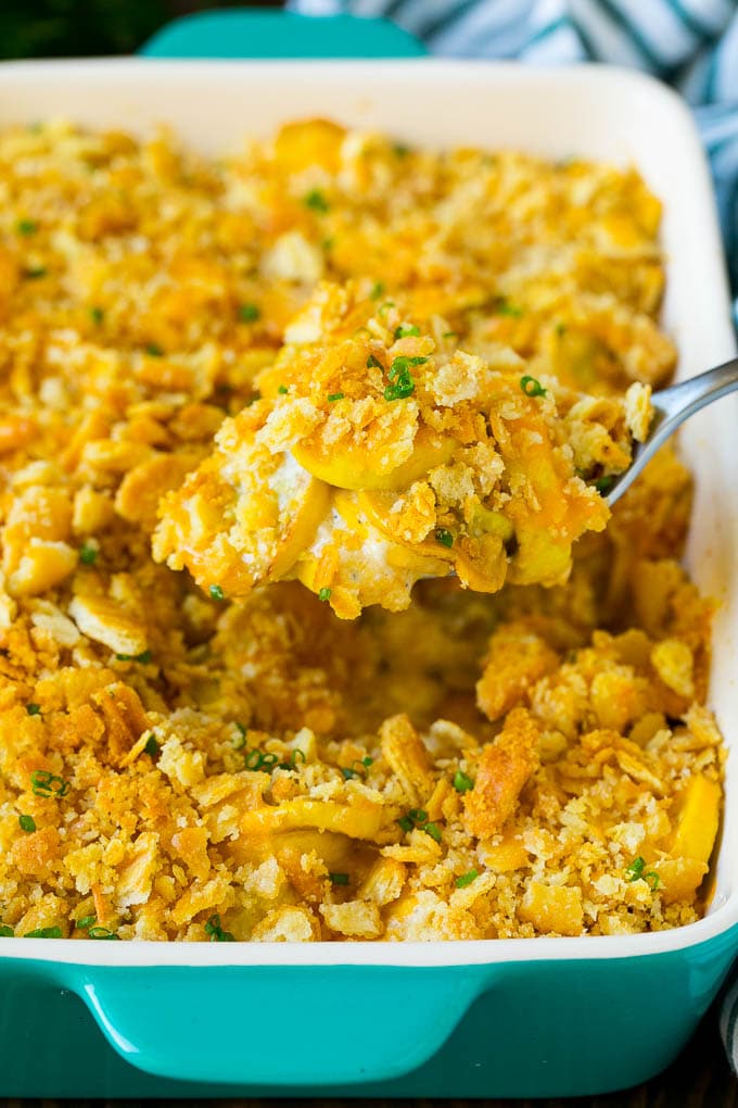A spoon serving up a portion of cheesy squash casserole.