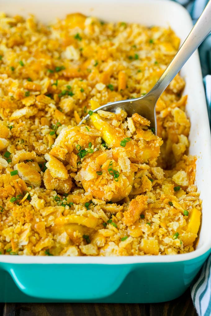 A serving spoon in a dish of squash casserole.