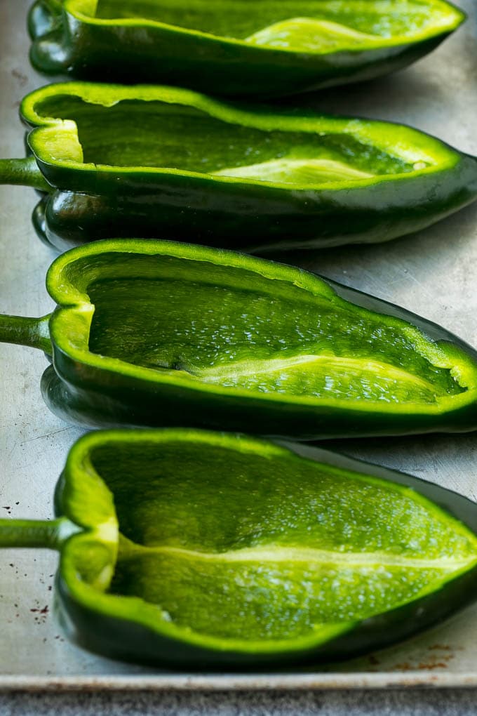 Hollowed out poblano peppers on a pan.