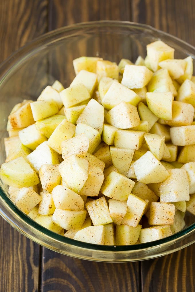 Diced apples tossed with sugar and cinnamon in a bowl.