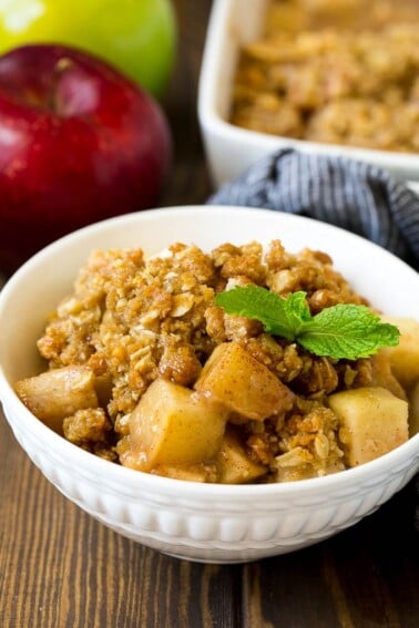 A bowl of apple crisp garnished with a sprig of mint.