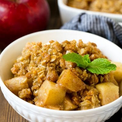 A bowl of apple crisp garnished with a sprig of mint.