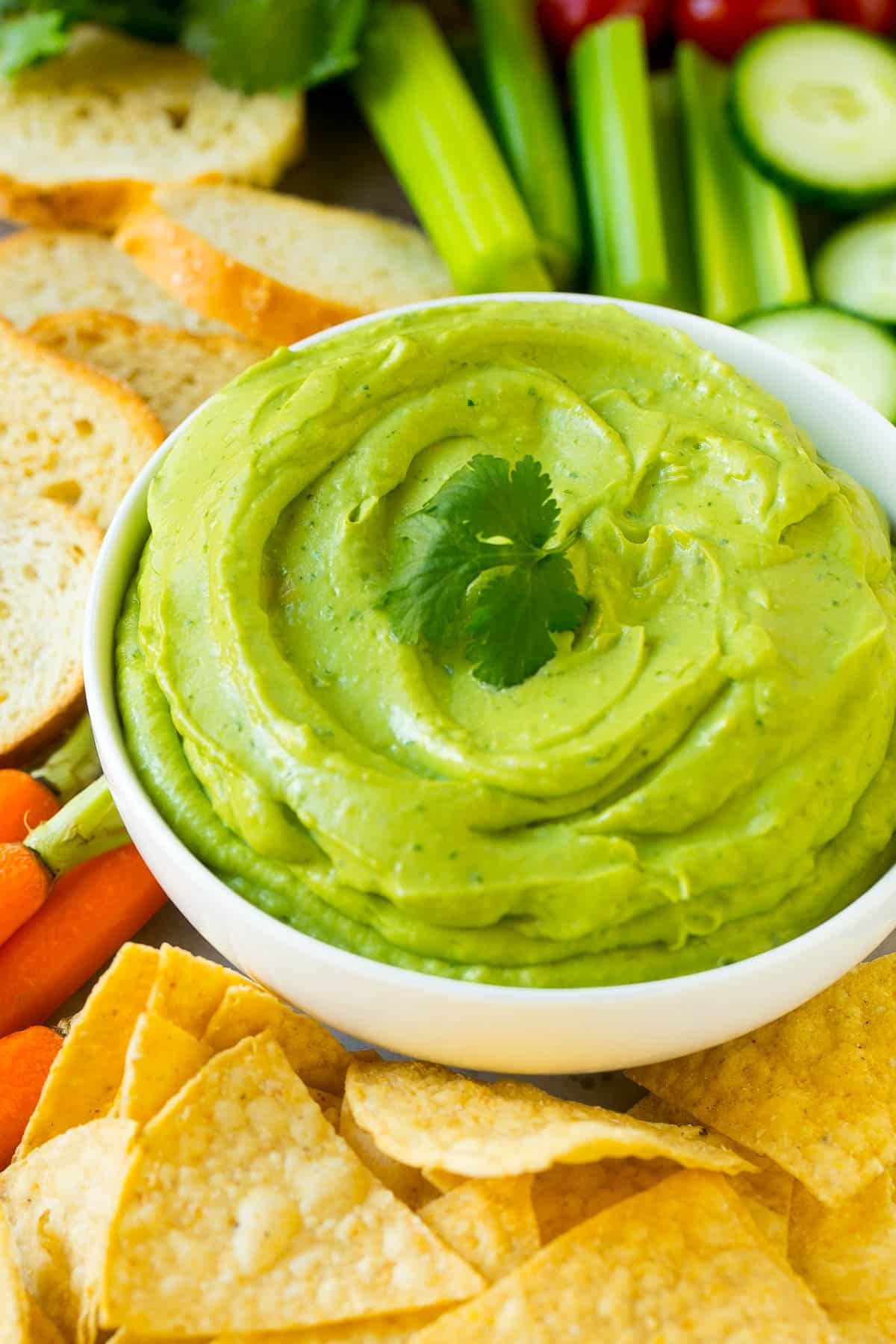 Creamy dip in a white bowl served with tortilla chips.