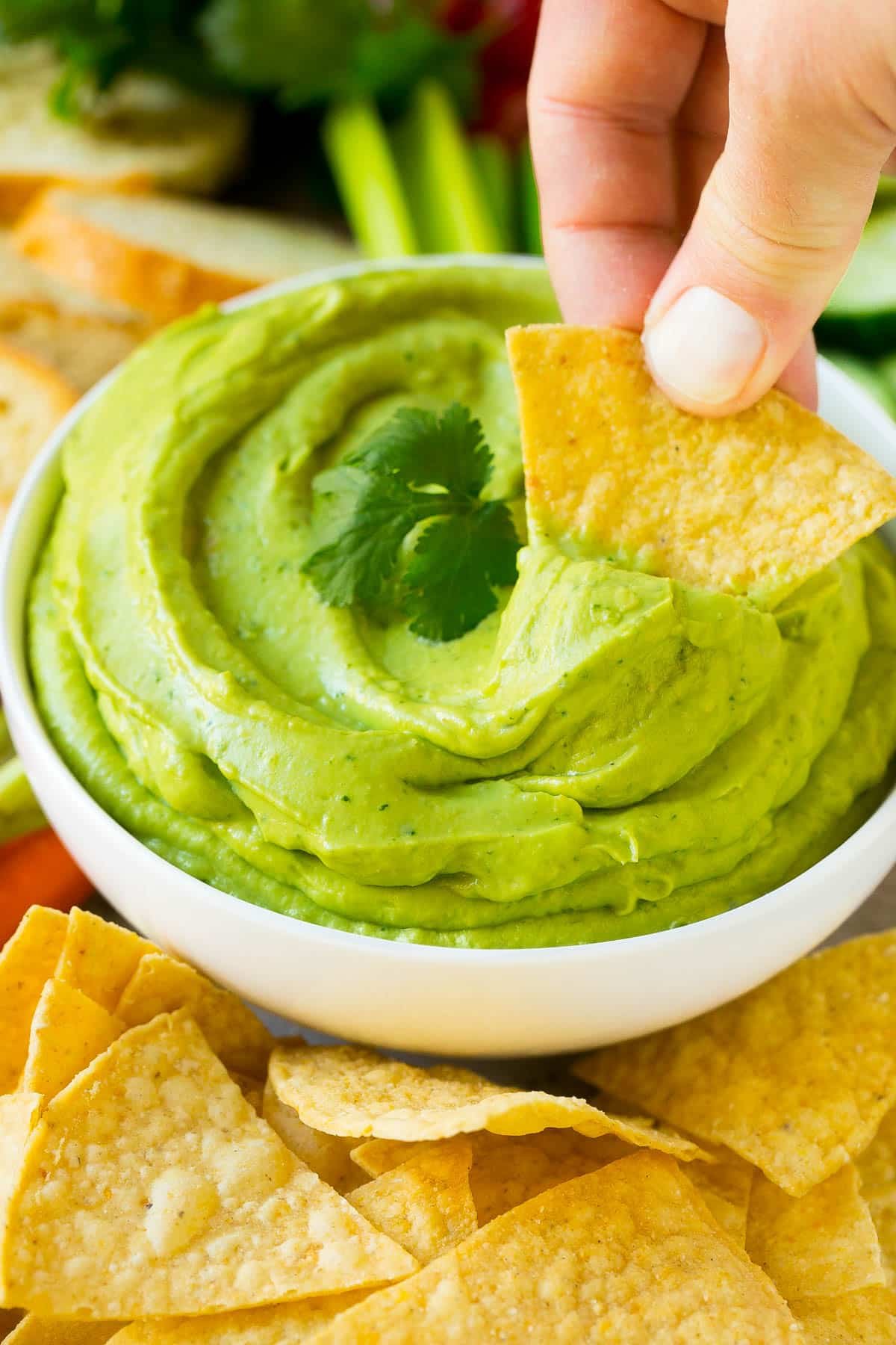 A tortilla chip scooping up a serving of avocado dip.