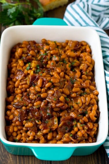 Bacon baked beans in a serving dish garnished with parsley.