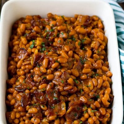 Bacon baked beans in a serving dish garnished with parsley.