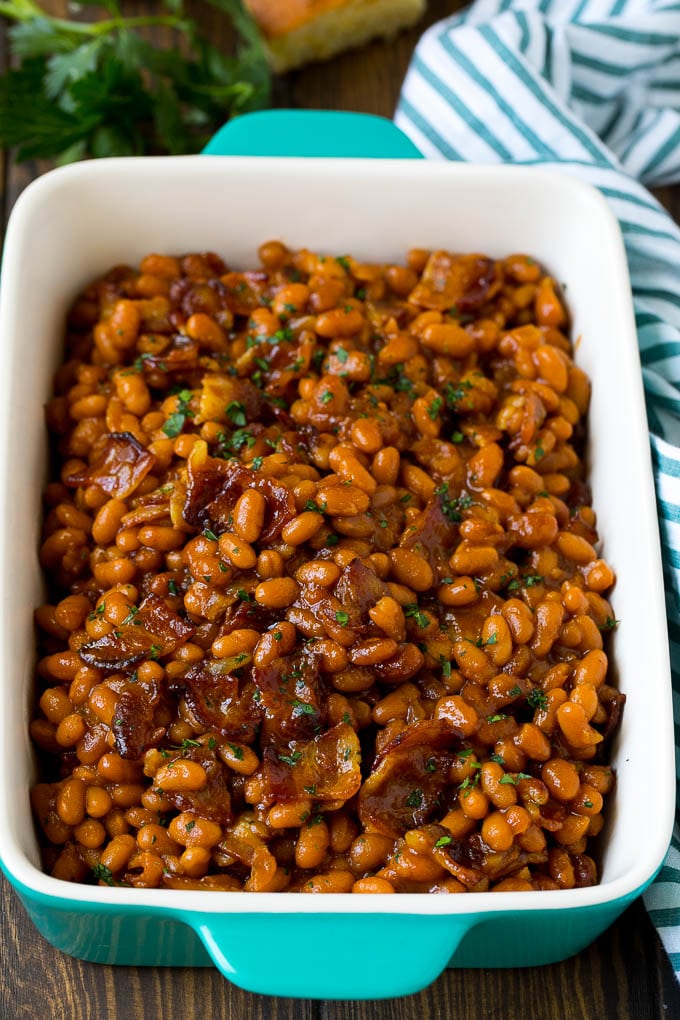 Bacon baked beans in a serving dish garnished with parsley.