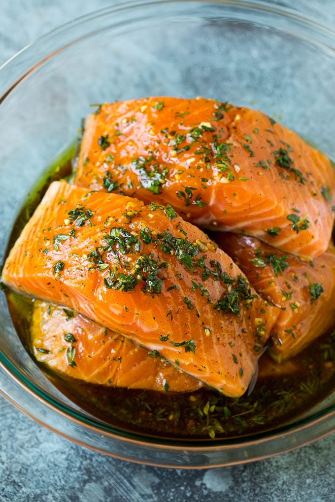 Salmon fillets in a bowl of olive oil, garlic and herbs.