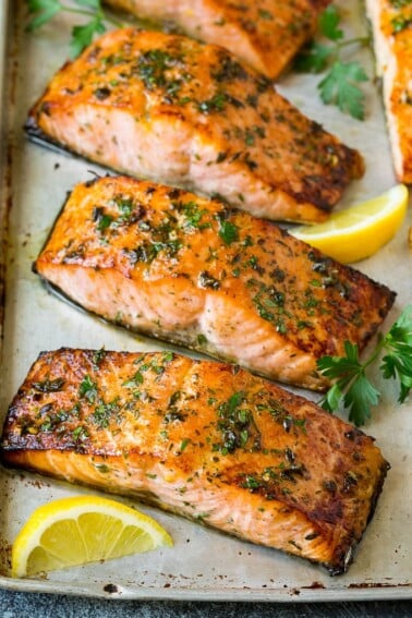 Broiled salmon with lemon wedges and parsley for garnish.