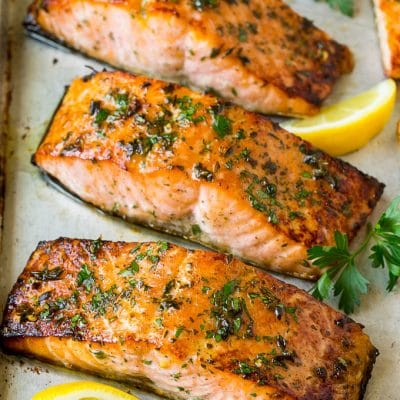 Broiled salmon with lemon wedges and parsley for garnish.