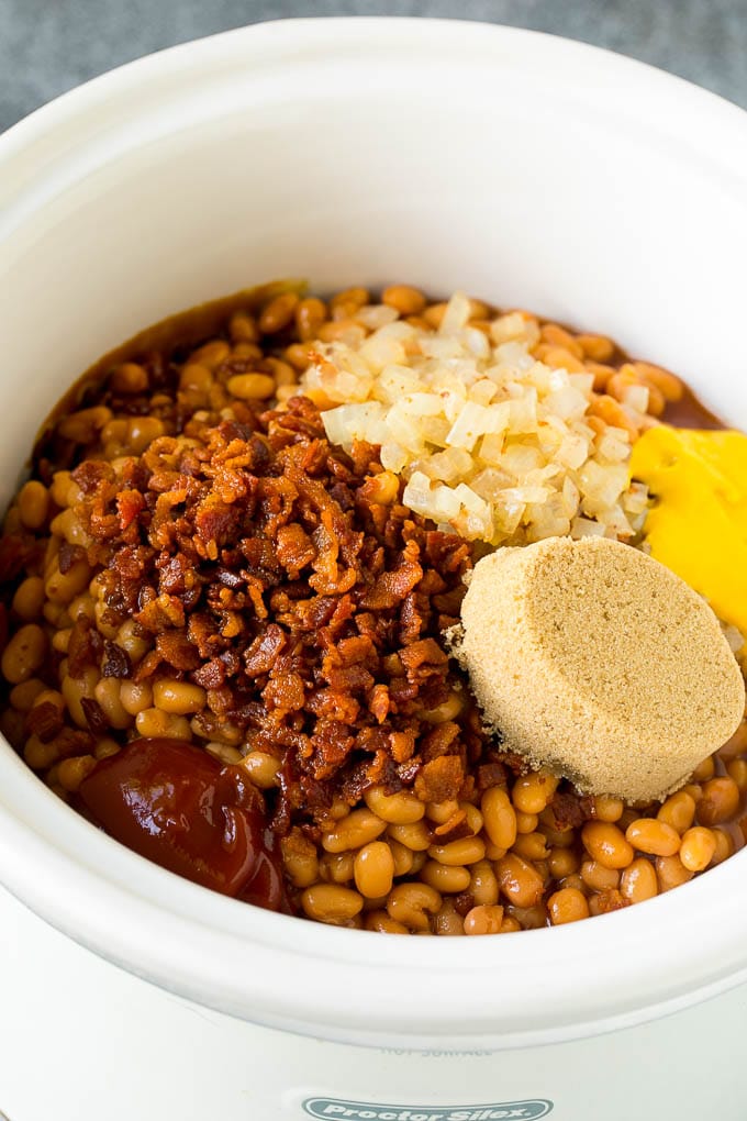 Beans in a slow cooker with bacon, onions, brown sugar and seasonings.