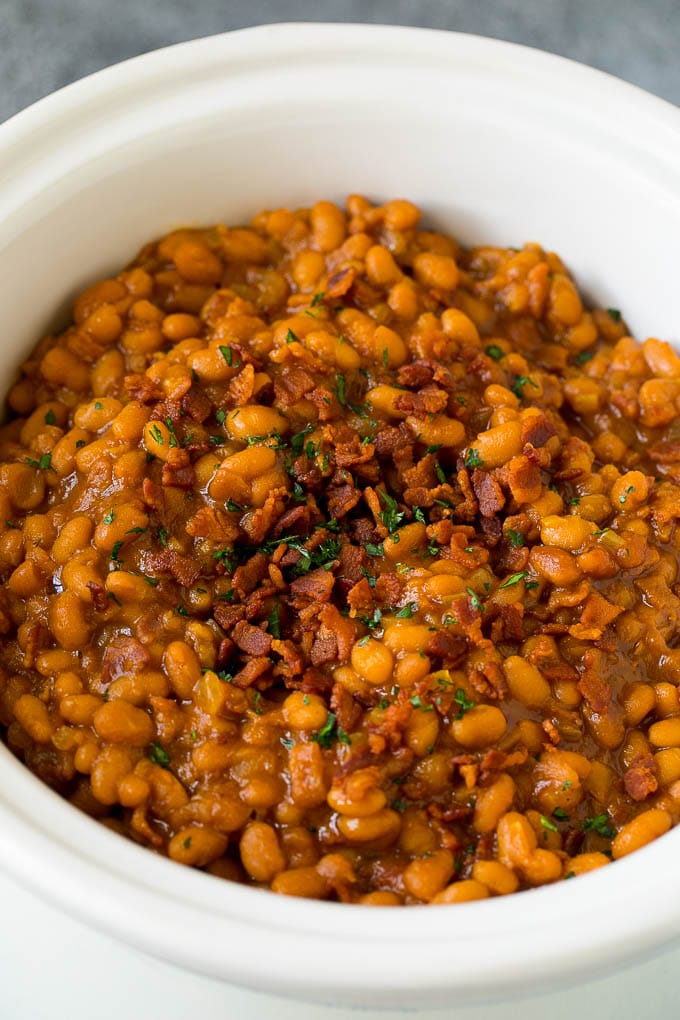 Slow cooker baked beans topped with bacon and parsley.