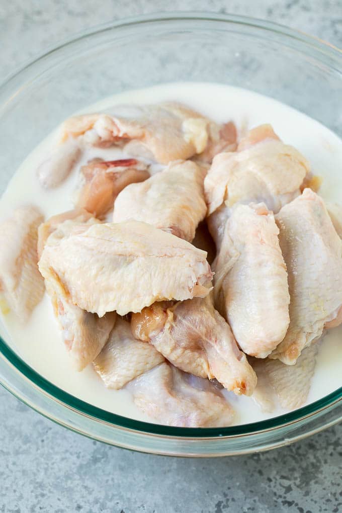 Chicken wings in a bowl of buttermilk.