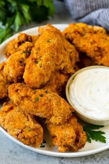 A plate of fried chicken wings served with ranch dip.