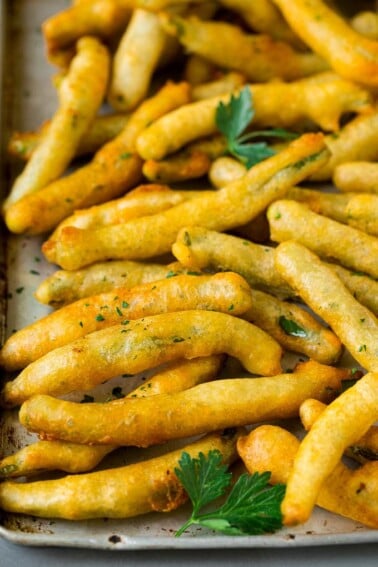 A sheet pan of fried green beans garnished with chopped parsley.