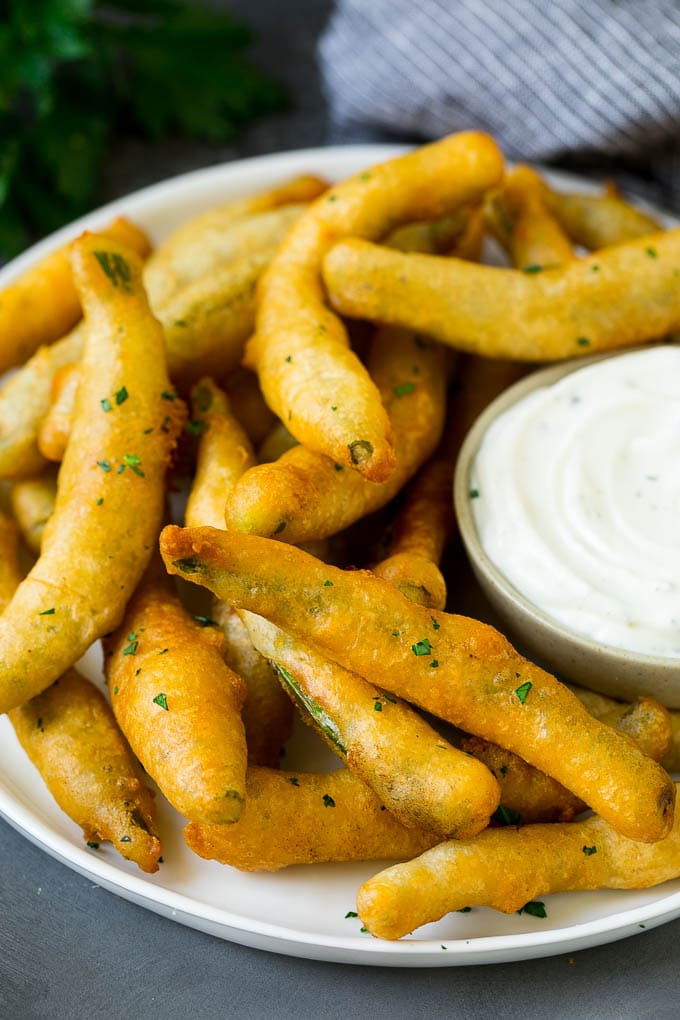 A plate of fried green beans served with ranch dip.