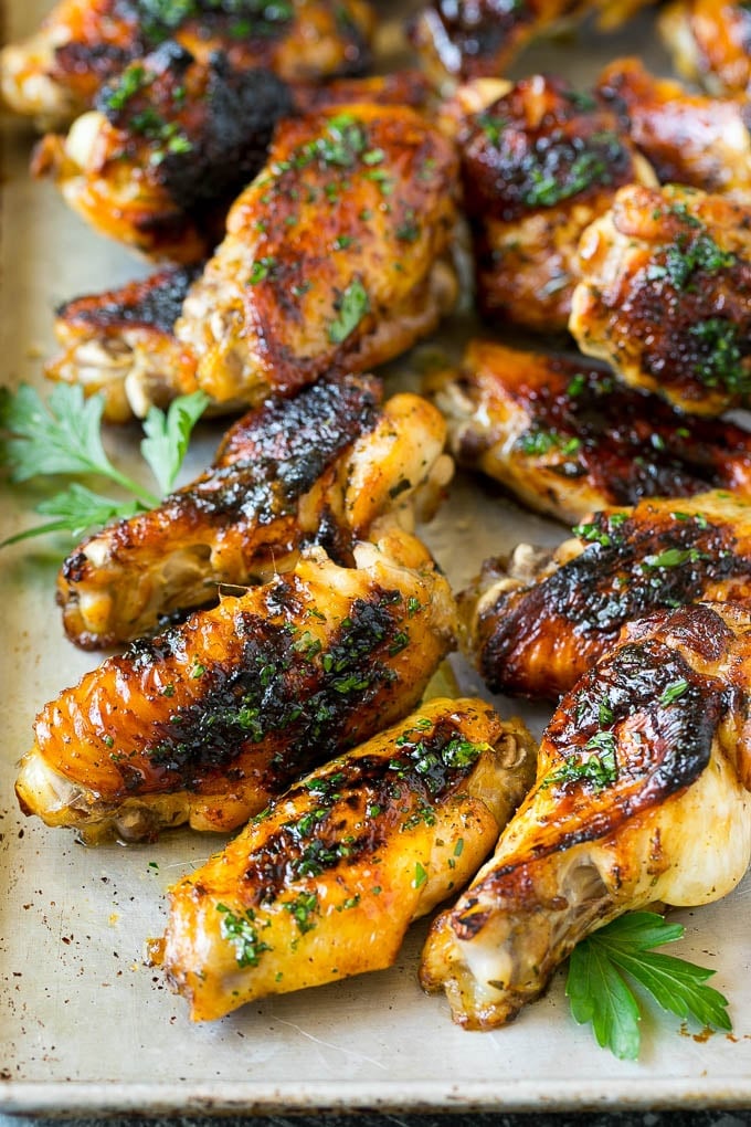 Grilled chicken wings on a sheet pan, garnished with parsley.