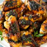 A plate of grilled chicken wings coated in herbs.