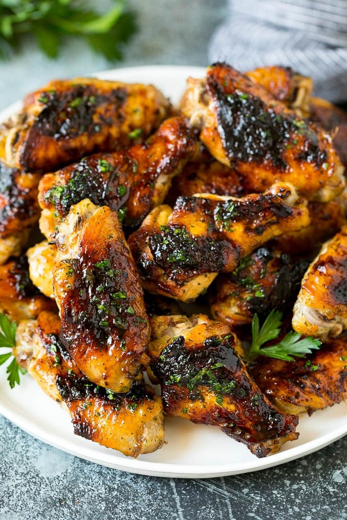 A plate of grilled chicken wings coated in herbs.