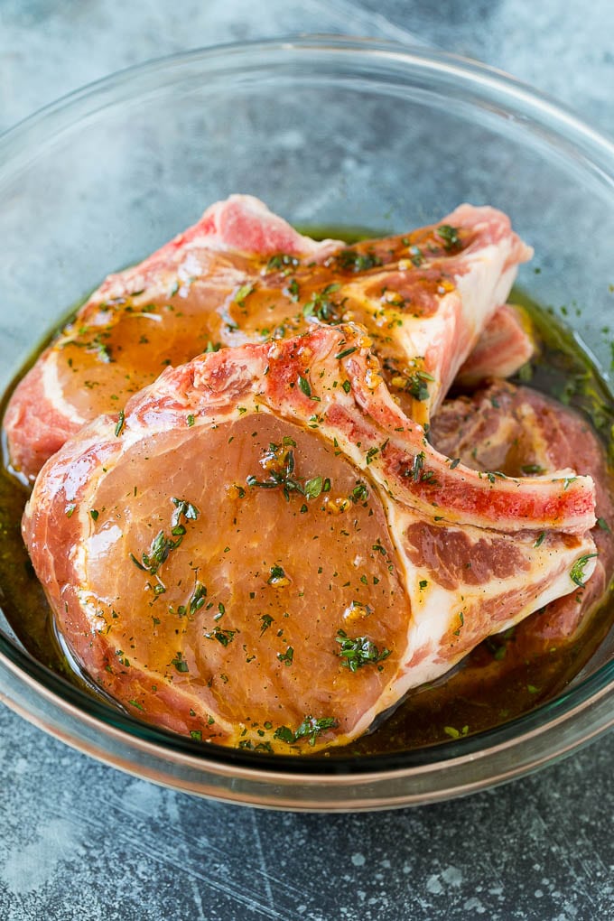 Pork chops in a bowl of marinade.