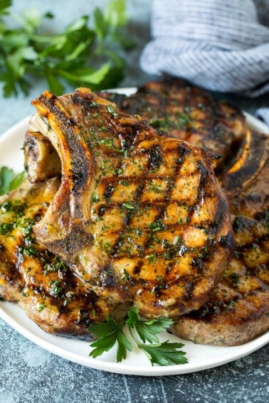 Grilled pork chops coated in marinade then cooked and garnished with parsley.