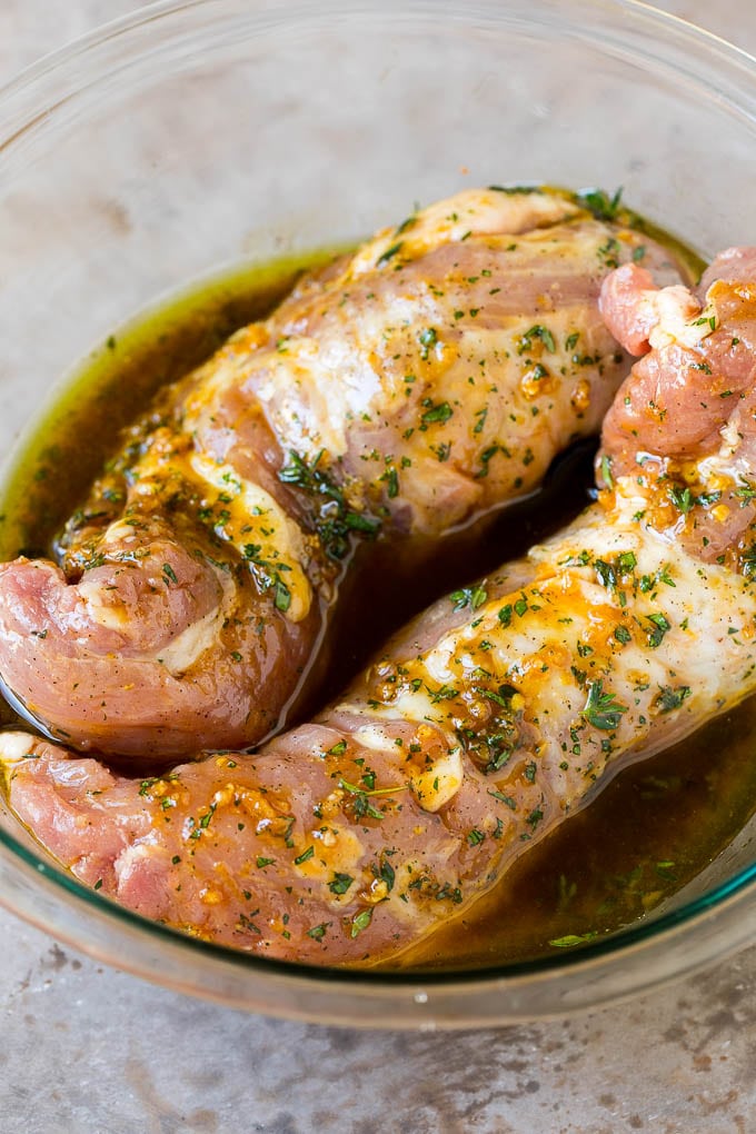 Pork tenderloin in a bowl of marinade.