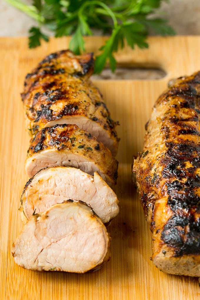 Sliced pork tenderloin on a cutting board.